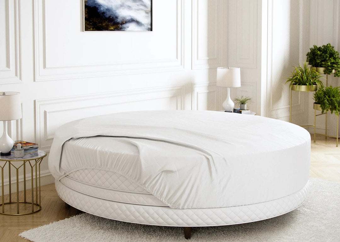 A white round mattress protector on a bed in a room with a light interior.